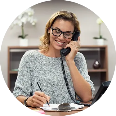 A smiling woman on desk talking on desk phone