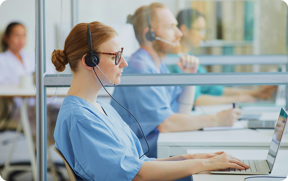 Female nurse wearing a headset and working at a computer desk