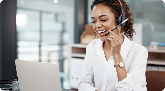 A female smiling wearing headset and using laptop